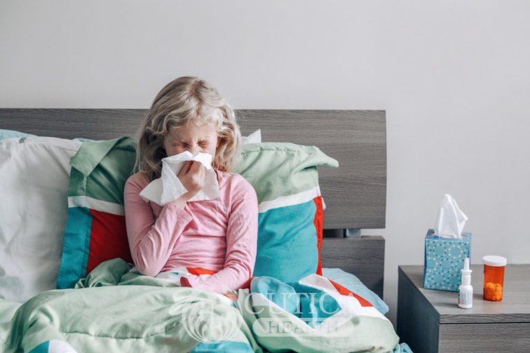 sick-ill-caucasian-girl-with-fever-sitting-in-bed-at-home-blowing-her-runny-nose-with-paper-tissue_t20_pLro4W-768x512